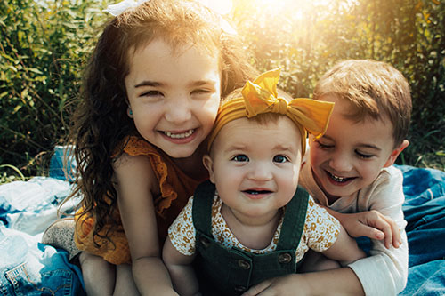 three siblings on blanket