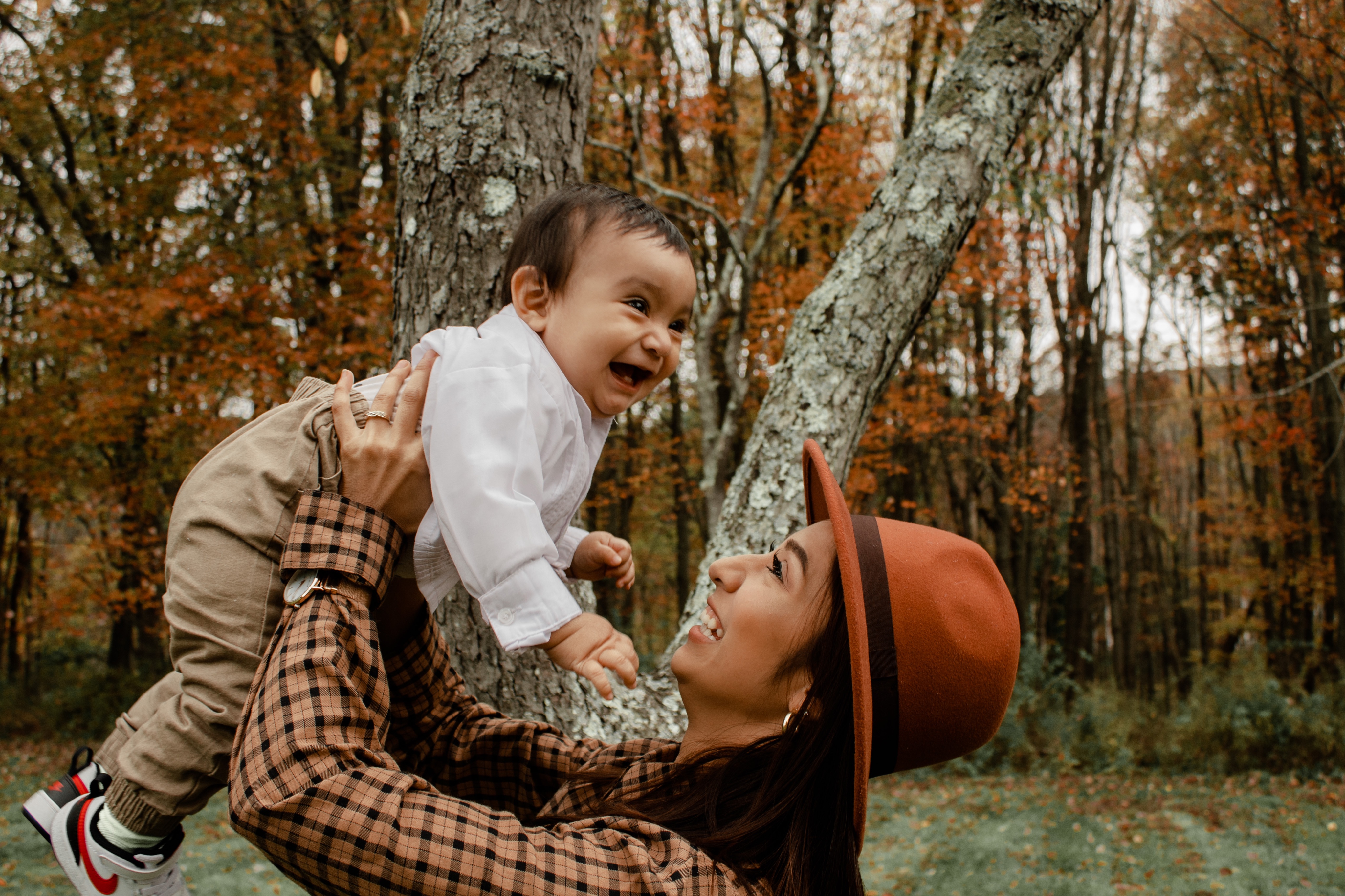 Mom holding up son with fall leaves