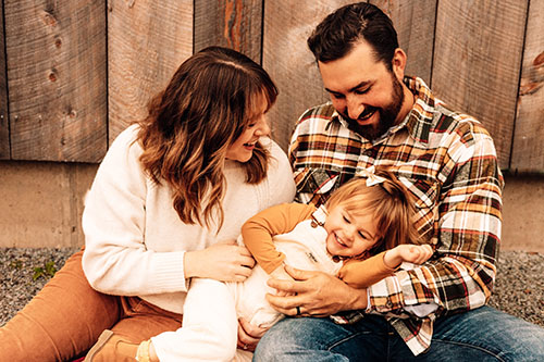 Parents tickling child by a barn