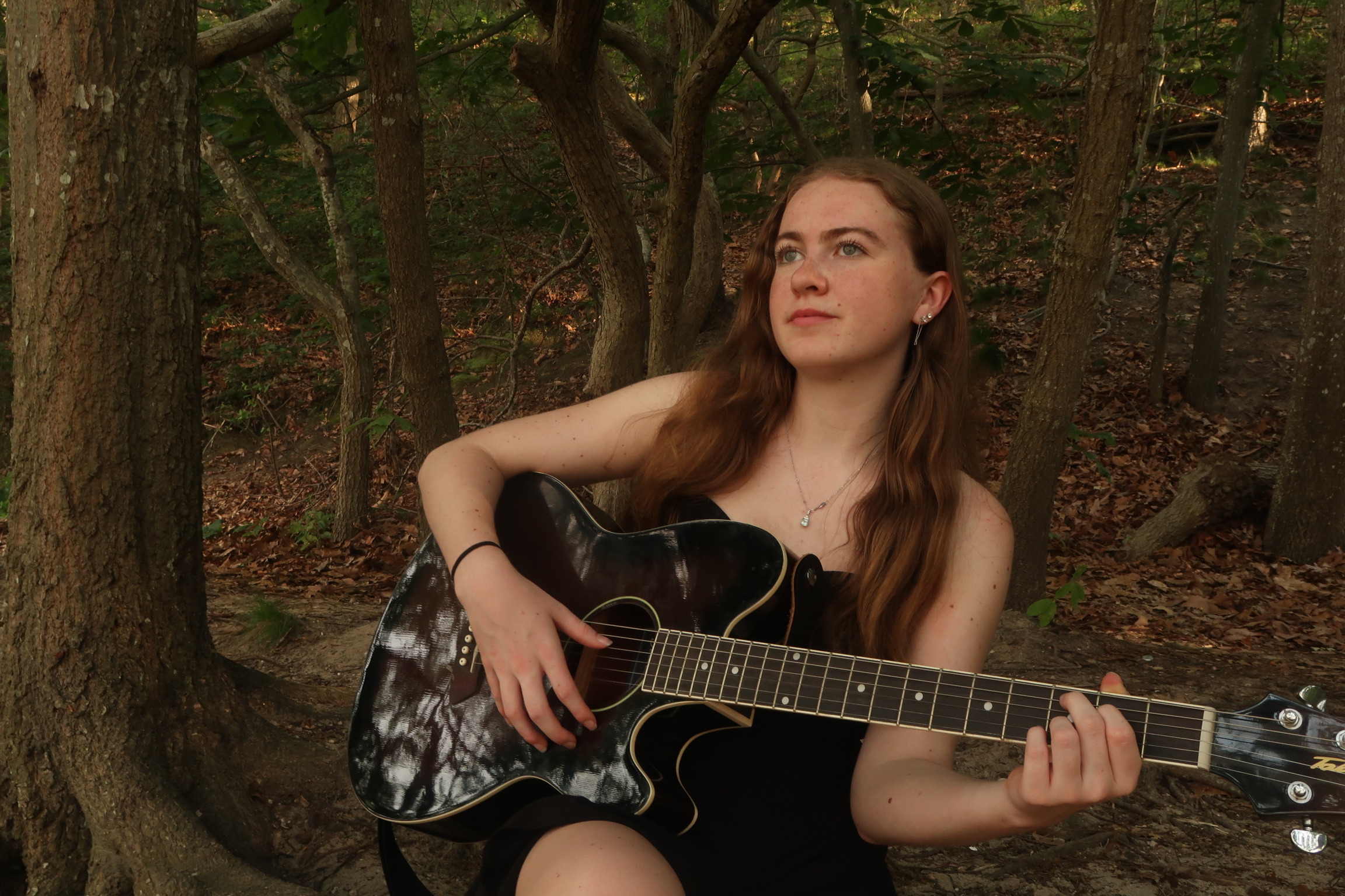 Sydneypacoustic sitting on a bench with her hands shielding her eyes from the sun